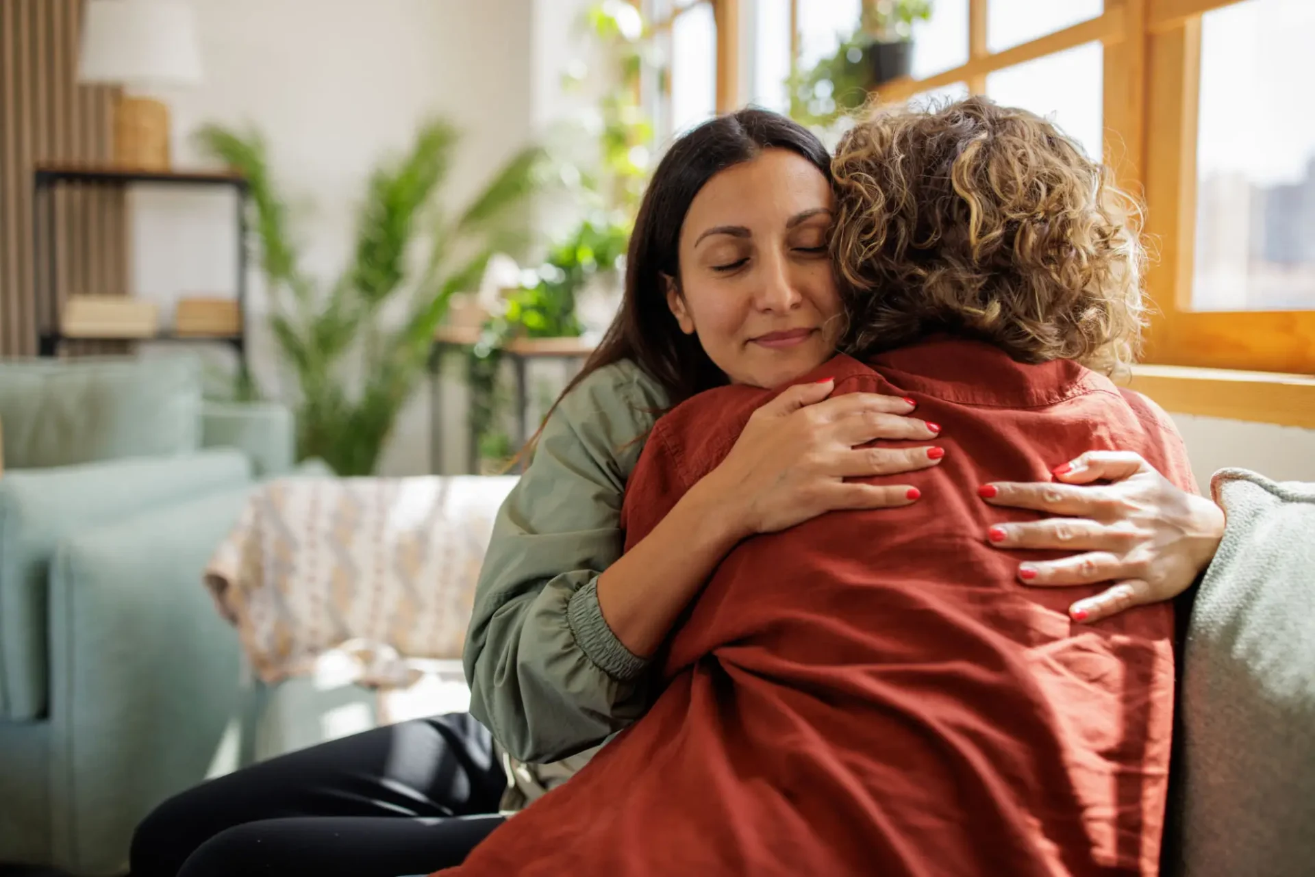 Two women sharing a warm, comforting hug indoors.